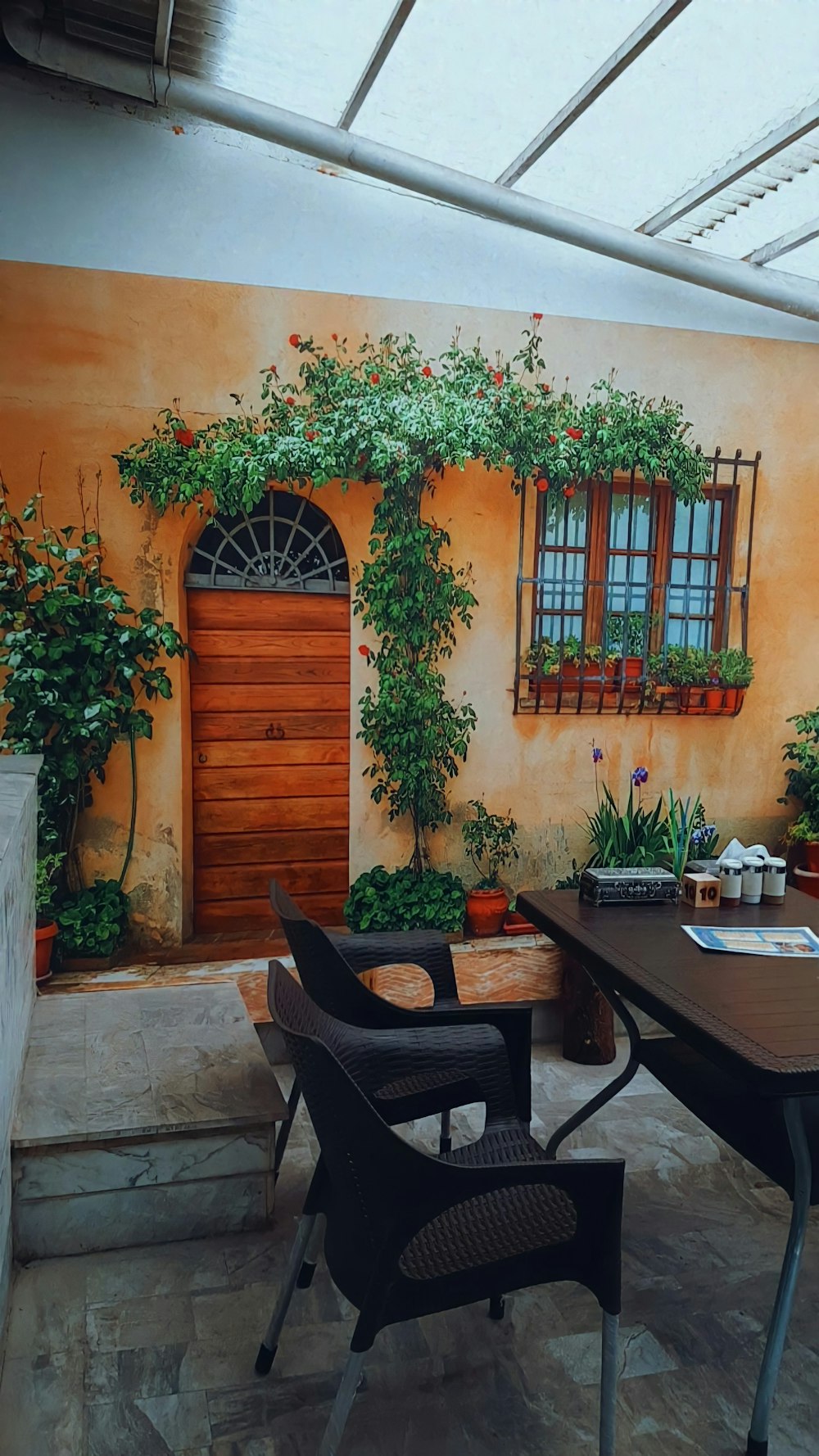 a patio with a table, chairs and potted plants