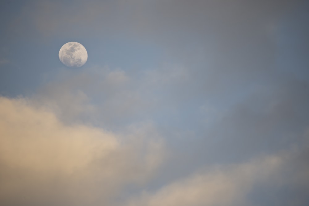 a full moon is seen through the clouds