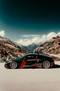 A sleek modern car parked on a scenic mountain road under clear blue sky