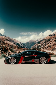 A sleek modern classic GT car parked on a scenic European coastal road.