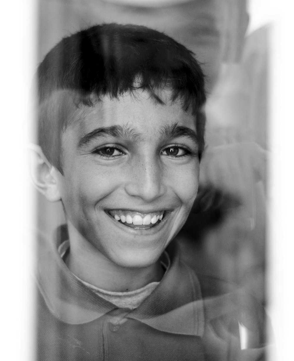 a black and white photo of a boy smiling