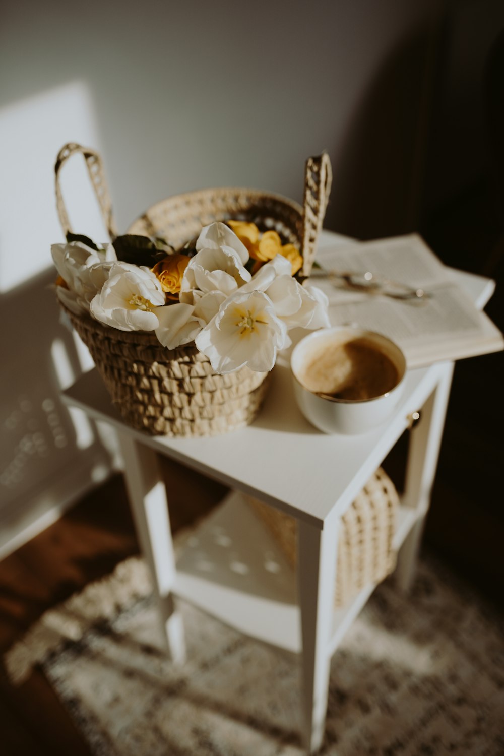 a table with a basket of flowers and a cup of coffee