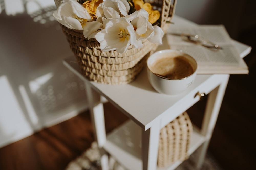 a basket of flowers and a cup of coffee on a table