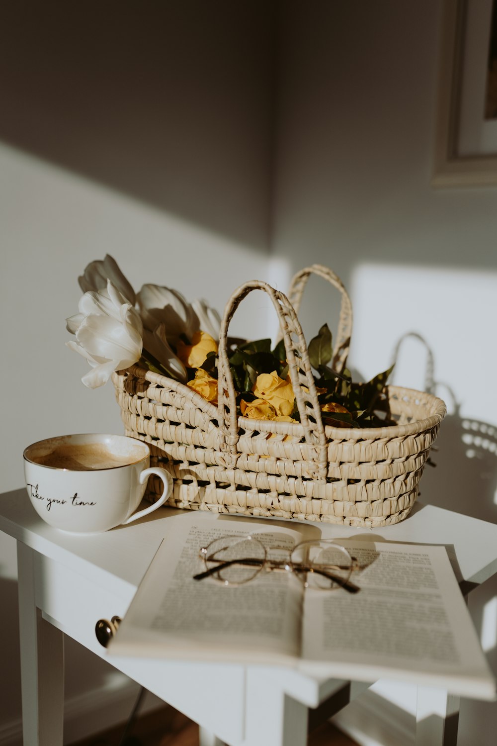 a basket of flowers sitting on a table next to a cup of coffee