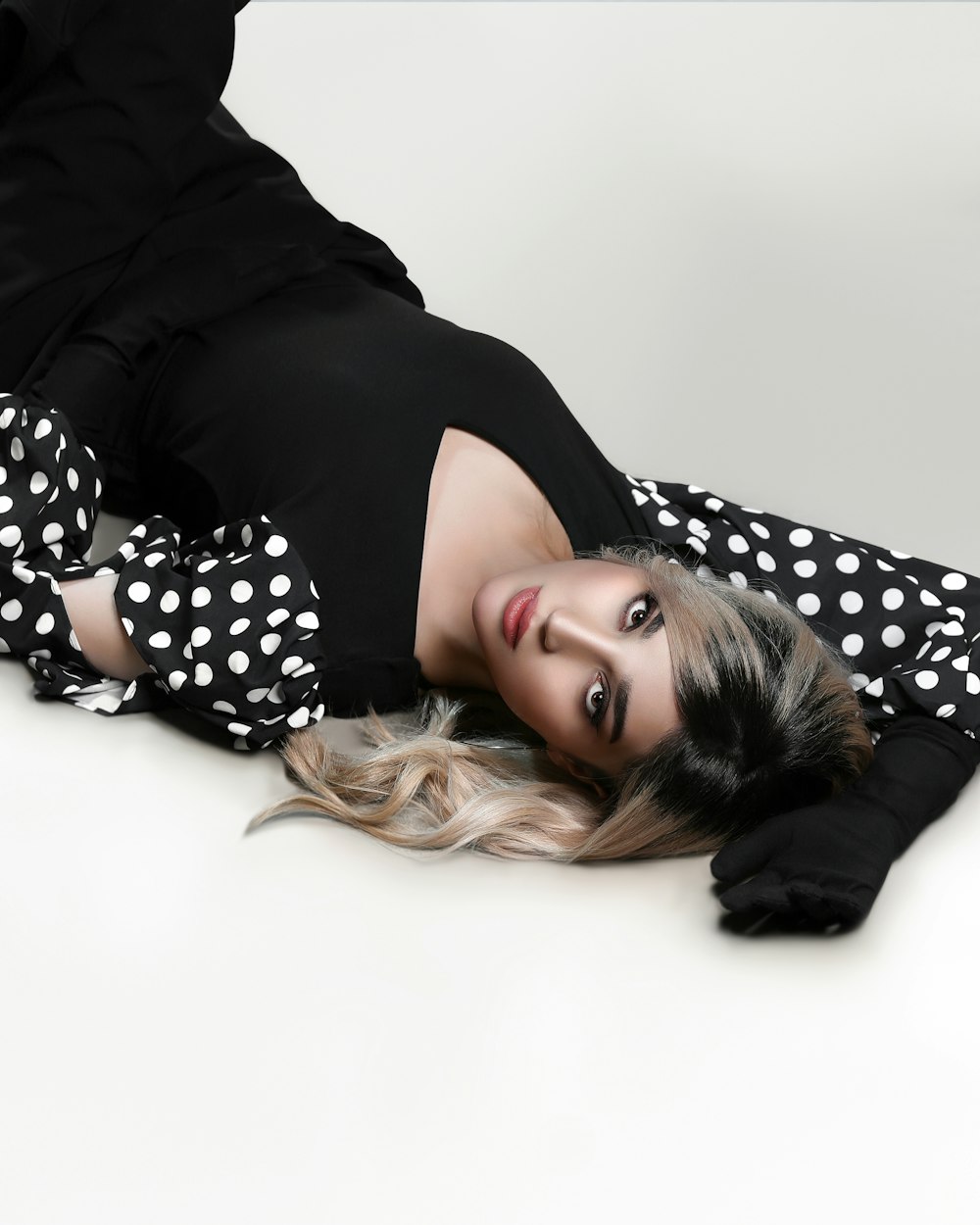 a woman laying on the ground wearing black and white polka dots