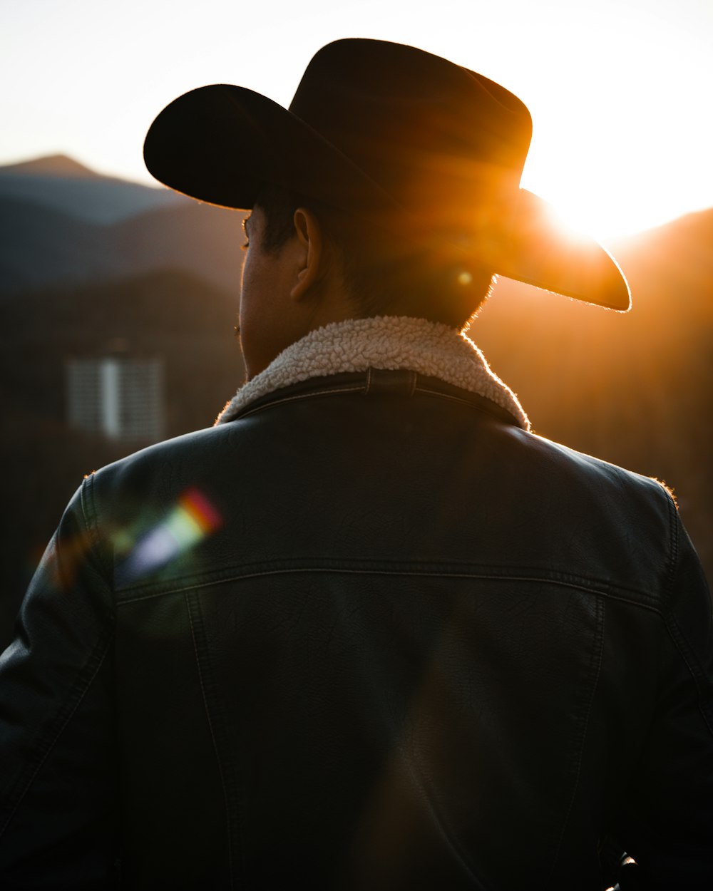 a man in a cowboy hat looking at the sun