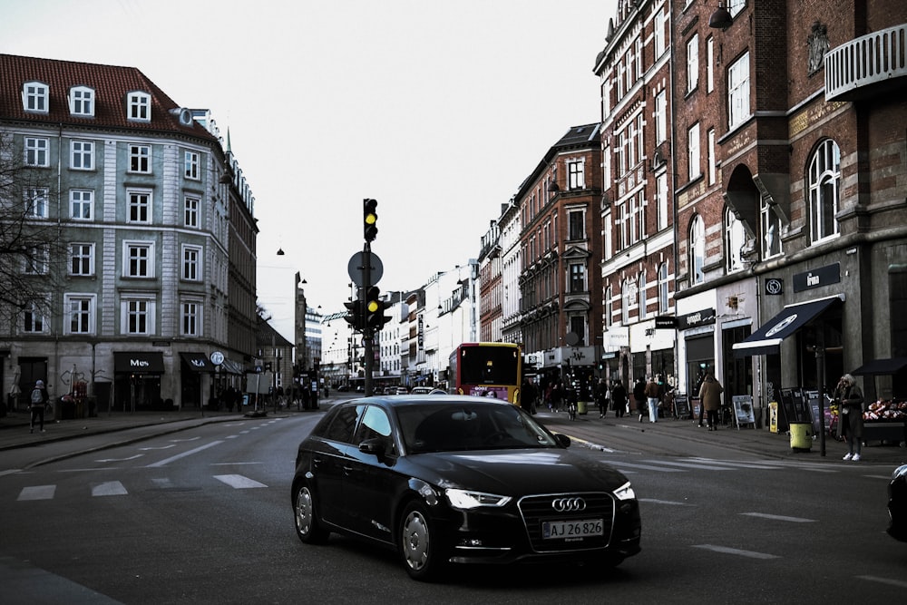 a black car driving down a street next to tall buildings