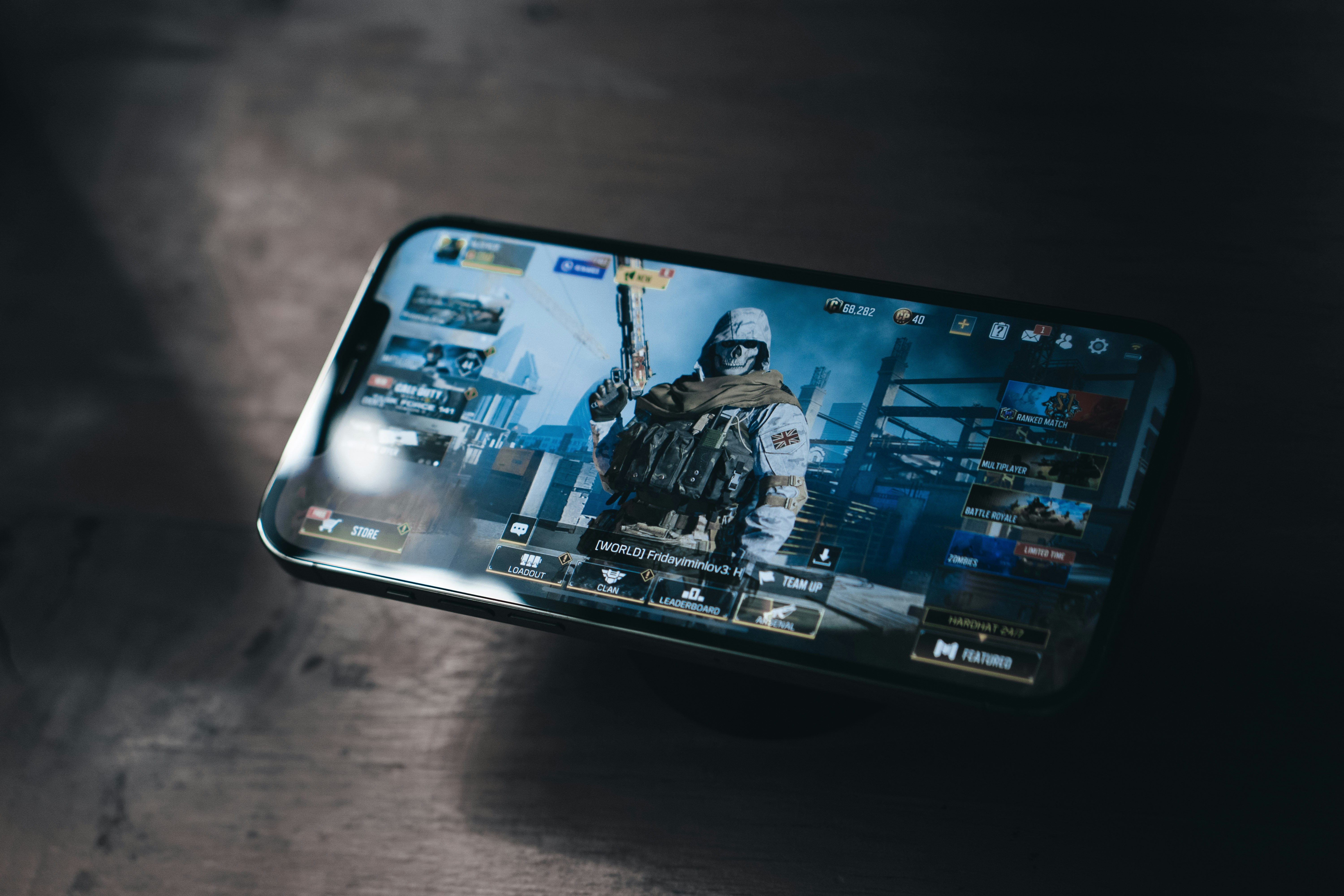 Graphite iPhone Pro Max with the Call of Duty: Mobile video game by Activision on screen. With a dark gradient dramatic light to it.