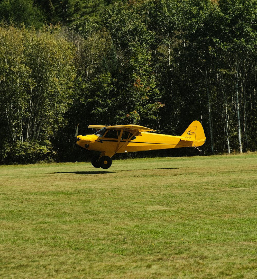 a small yellow plane sitting on top of a lush green field