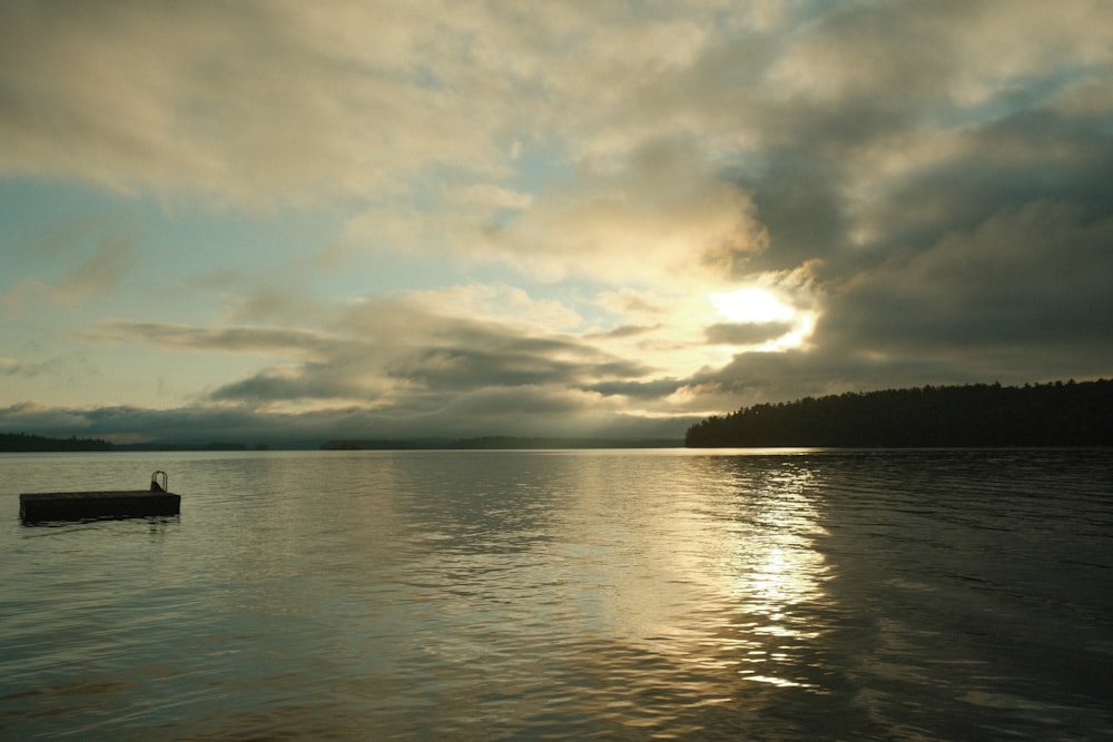 a boat floating on top of a lake under a cloudy sky