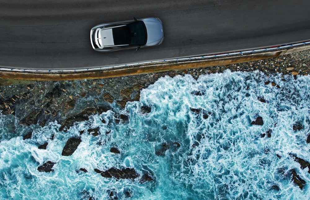 an aerial view of a car driving along the ocean