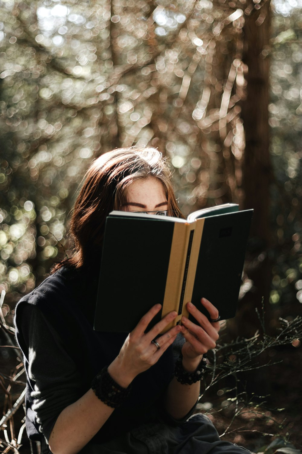 a woman sitting in the woods reading a book