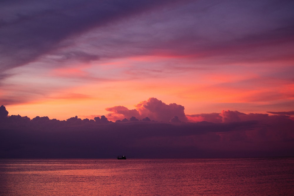 a boat floating in the ocean at sunset