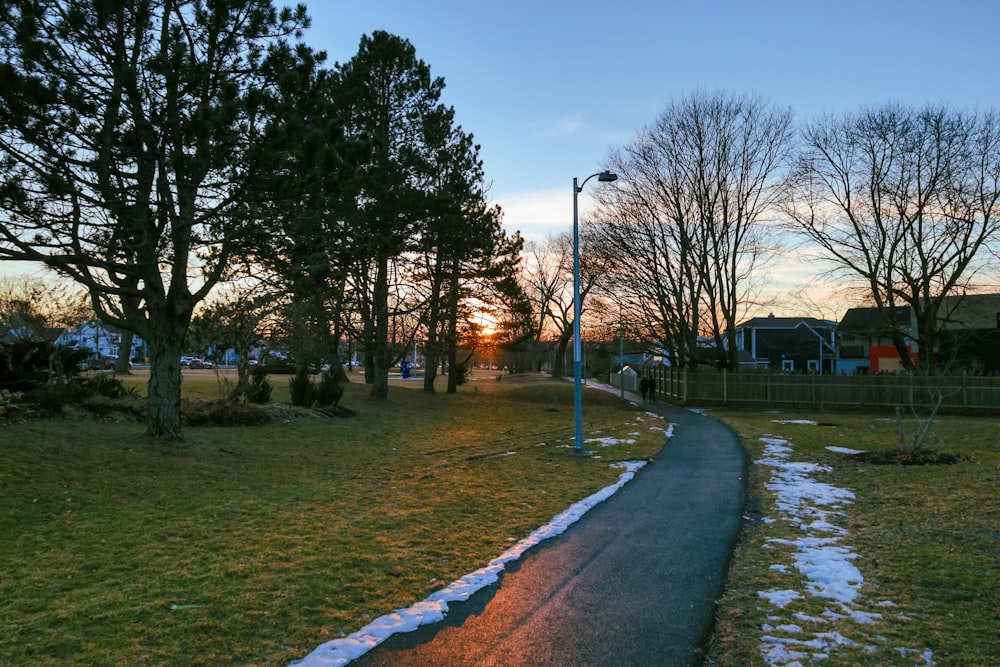 the sun is setting behind the trees on the side of the road