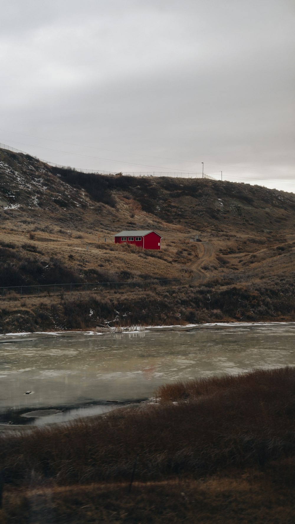 a red barn sitting on top of a hill next to a river
