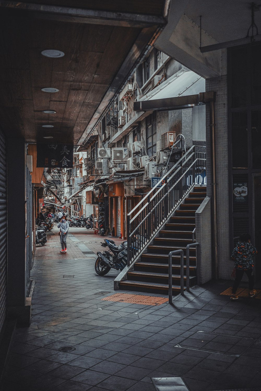 a man walking down a street next to a set of stairs