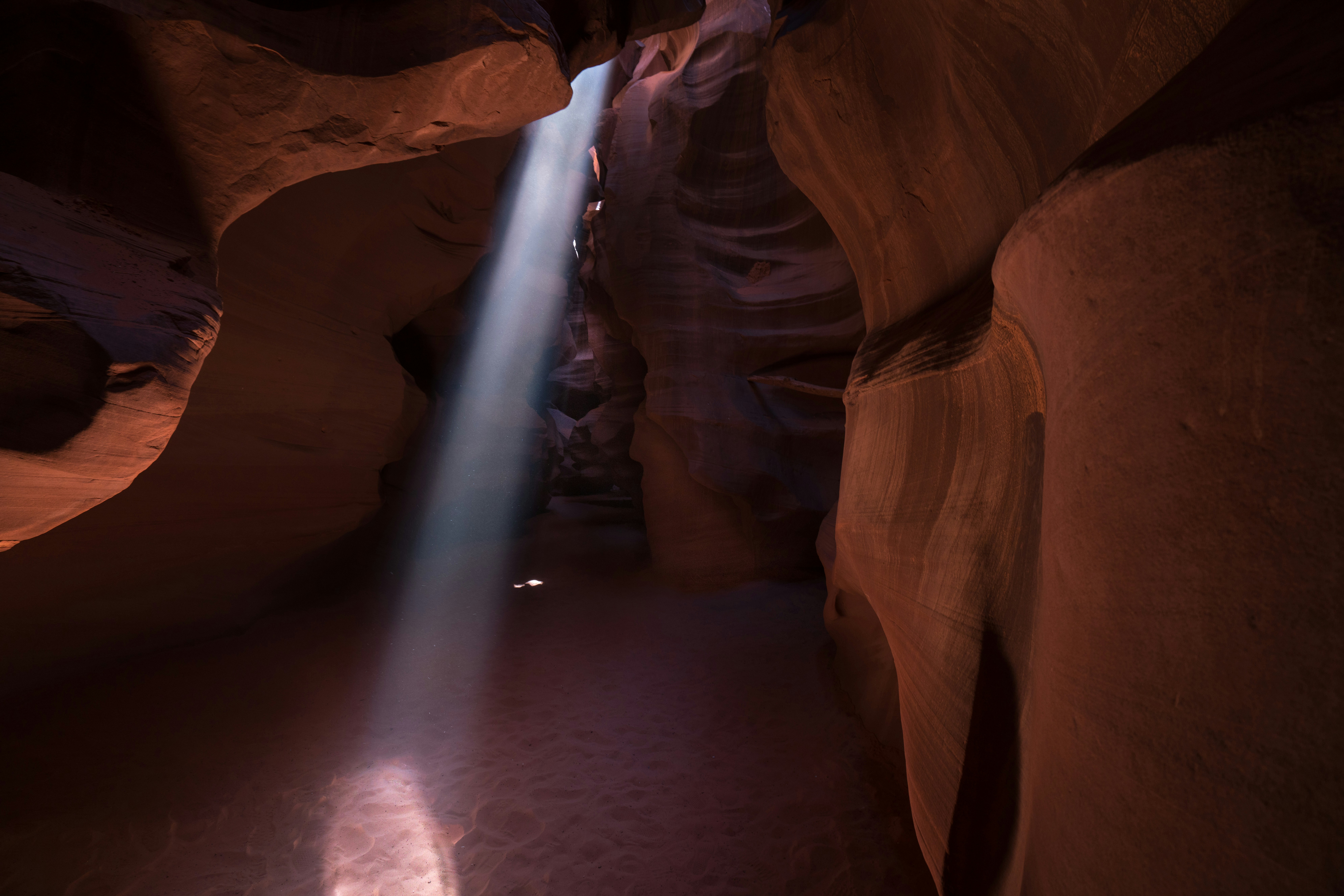 a light shines through a narrow slot in a canyon