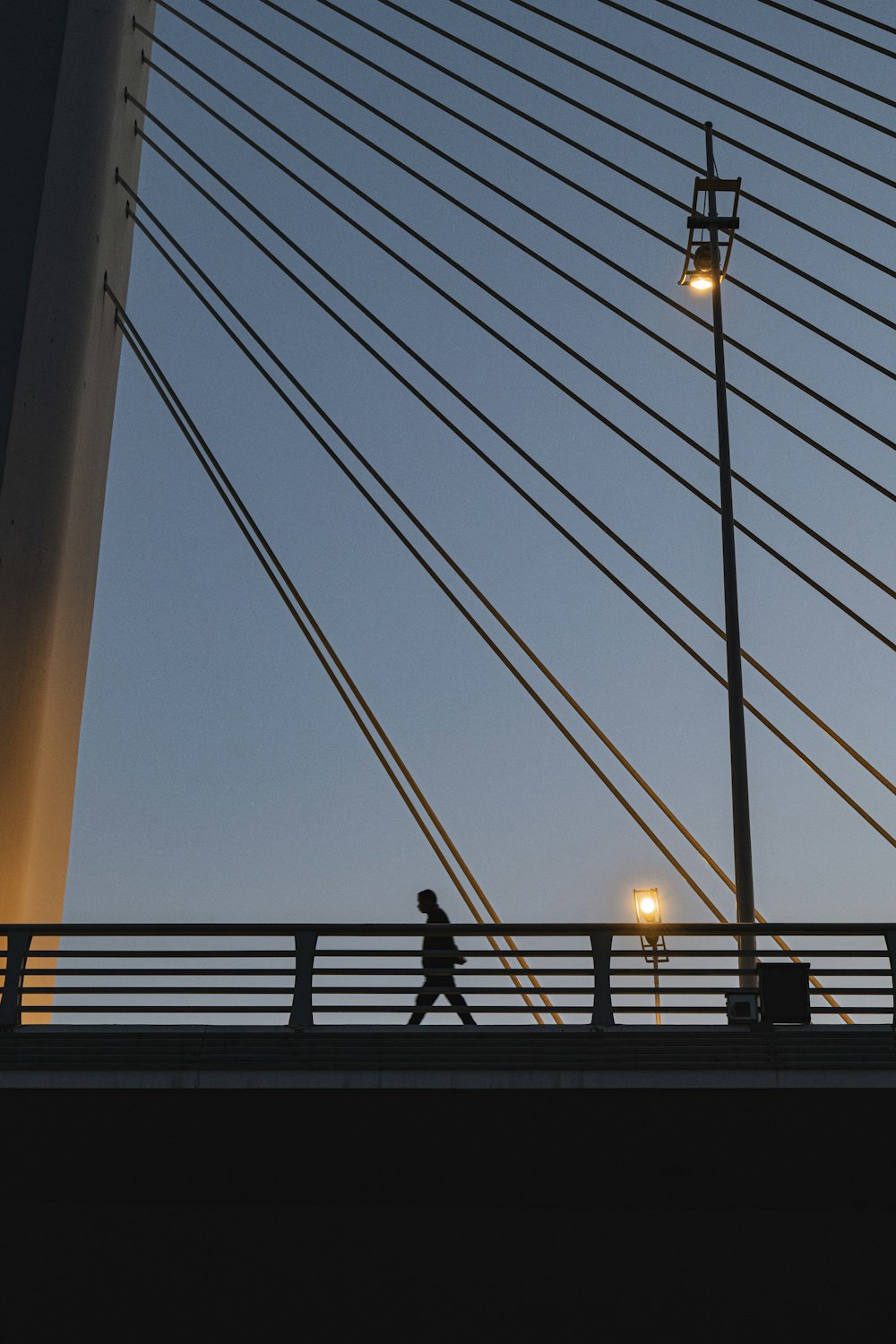 a person walking across a bridge at dusk