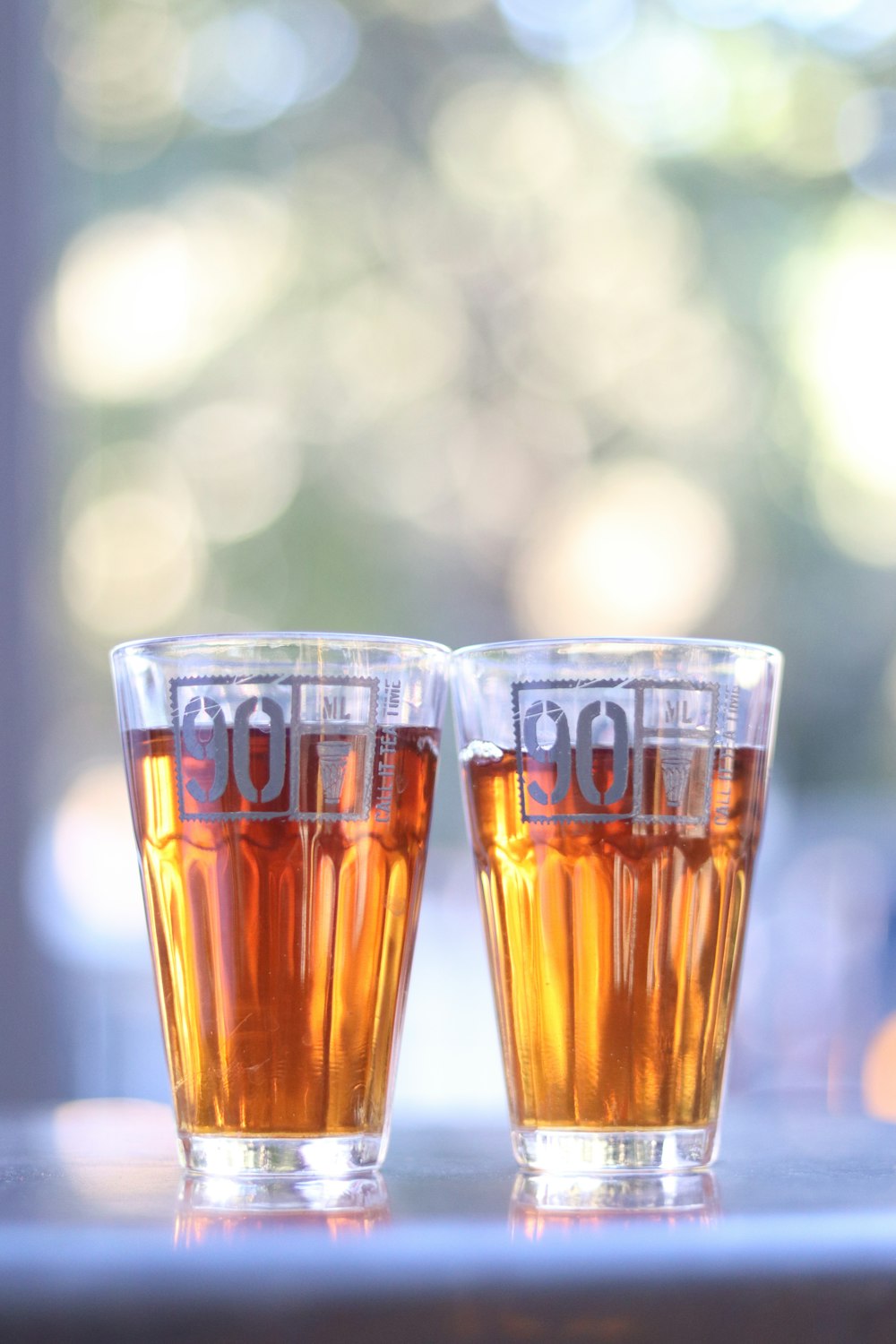 two glasses of beer sitting on top of a table