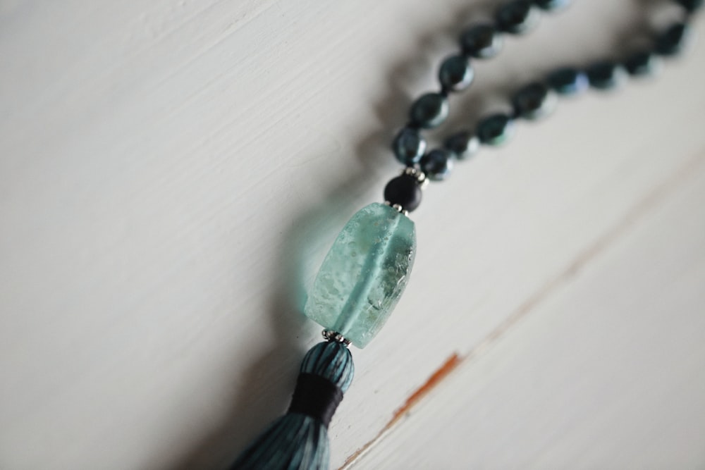 a tasseled necklace with a green bead and a tassel