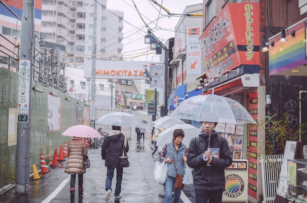 a group of people walking down a street holding umbrellas