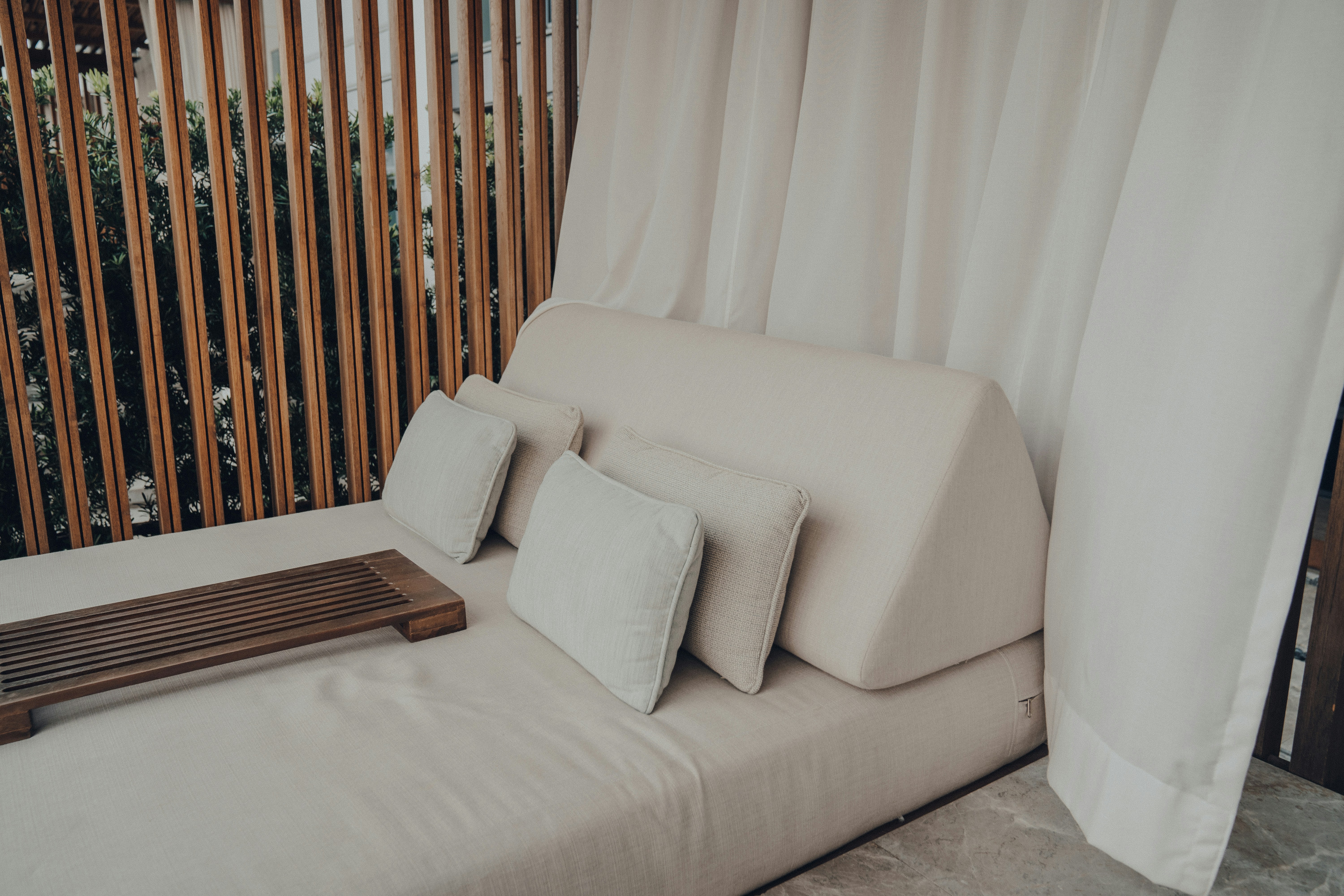 Sofa putih duduk di sebelah pagar kayu