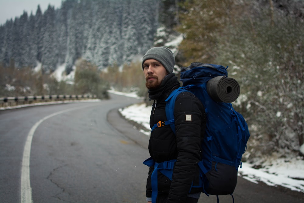 a man with a backpack standing on the side of a road