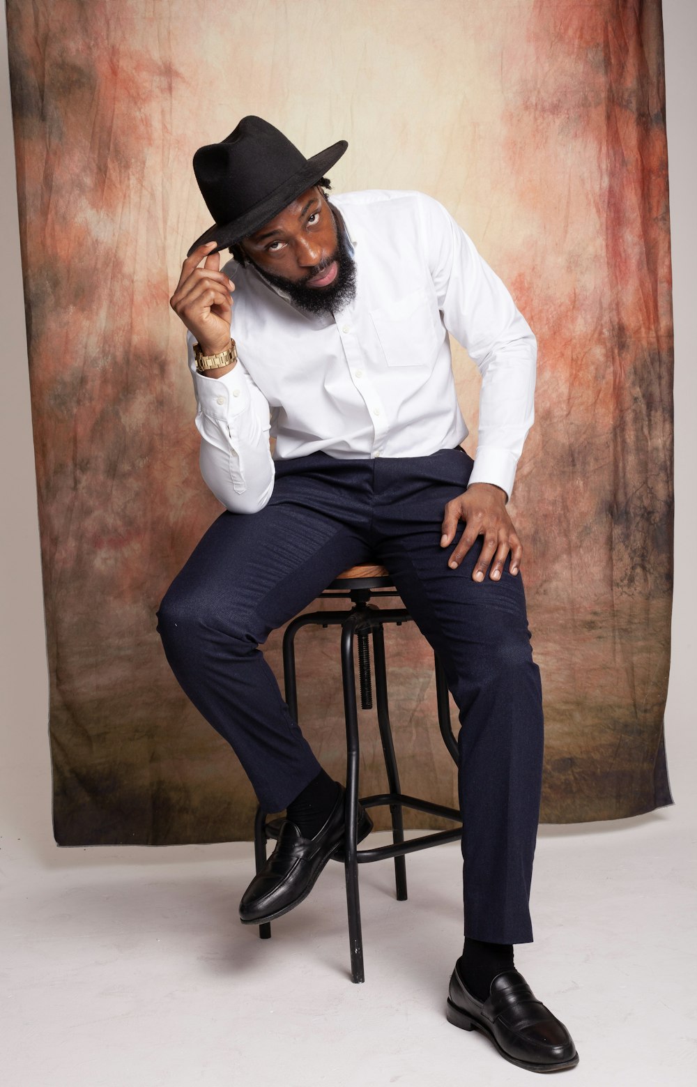 a man sitting on a stool wearing a hat