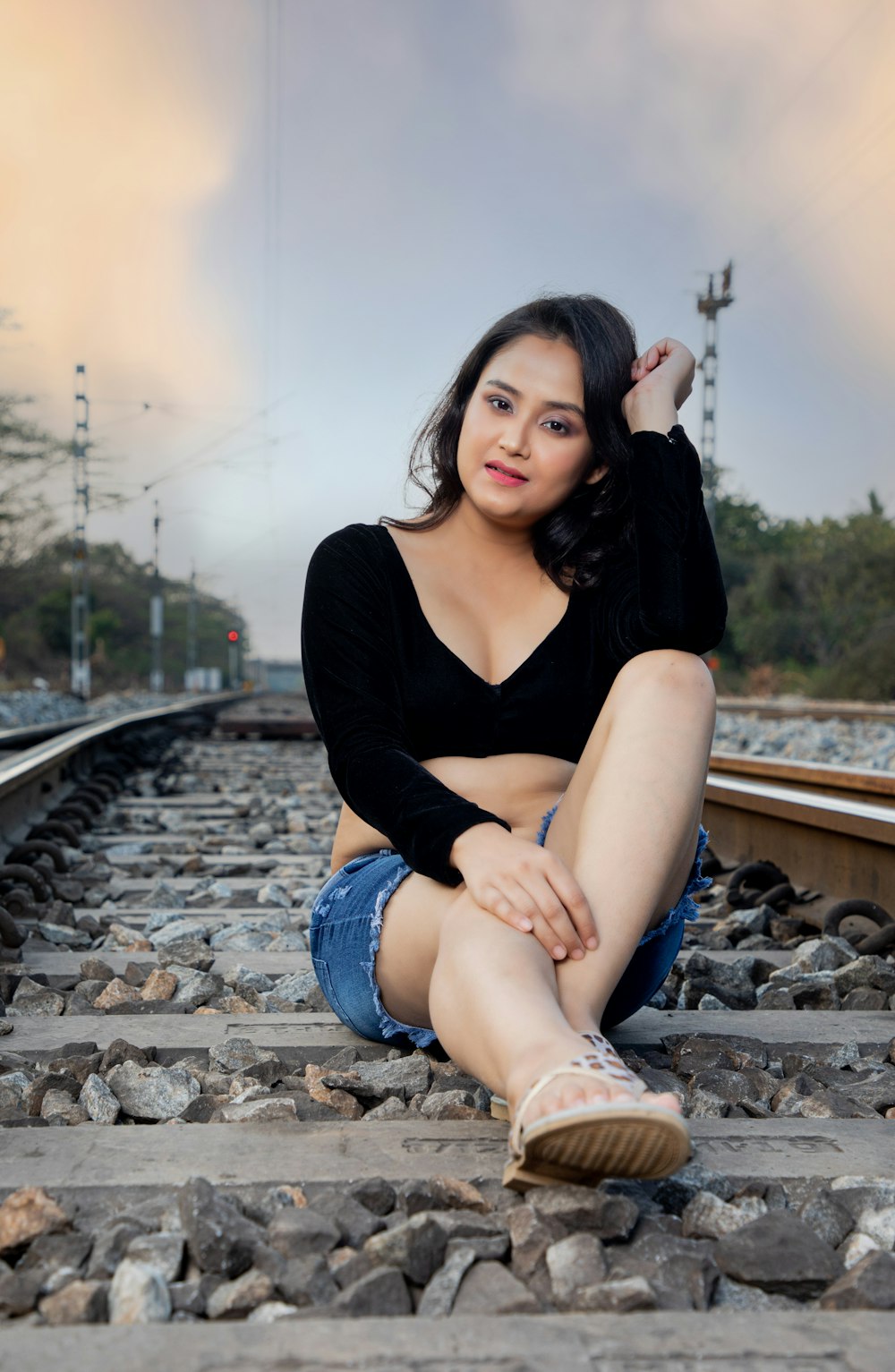 a woman sitting on a train track with her legs crossed