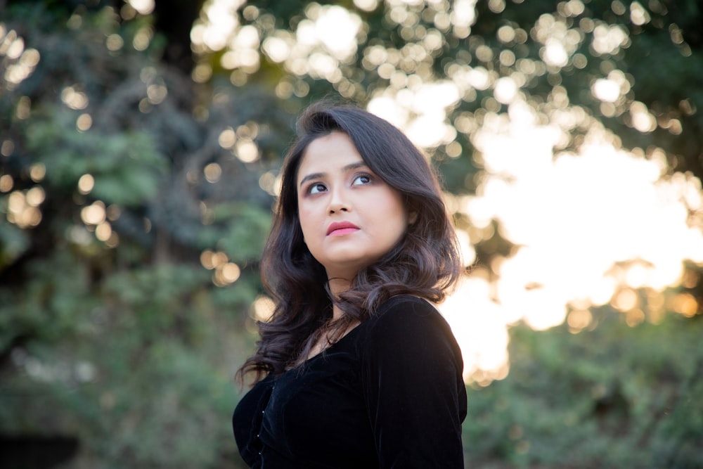 a woman standing in front of some trees