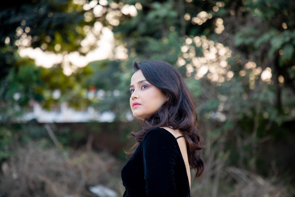 a woman in a black dress looking away from the camera