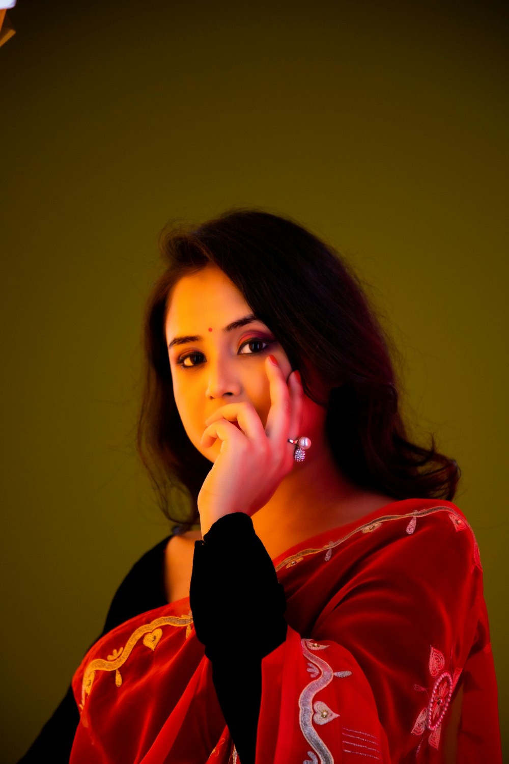 a woman in a red sari holding her hand to her face