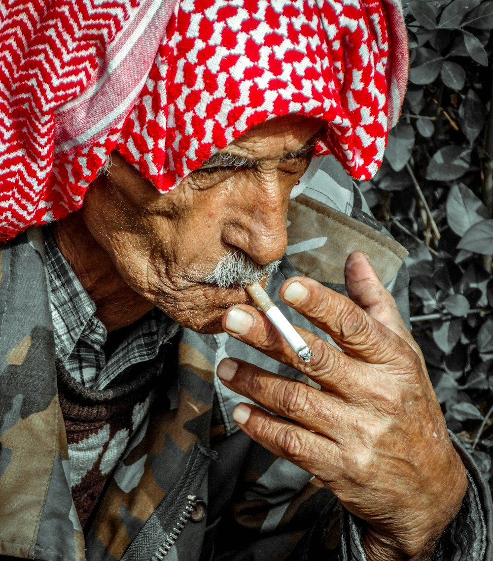 a man with a red and white turban smoking a cigarette