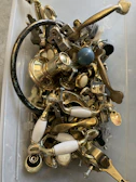Selection of metal accessories like hinges and locks laid out on a black industrial table.