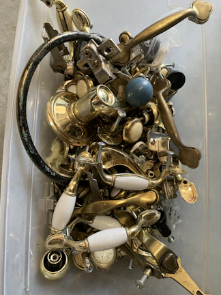 Selection of metal accessories like hinges and locks laid out on a black industrial table.