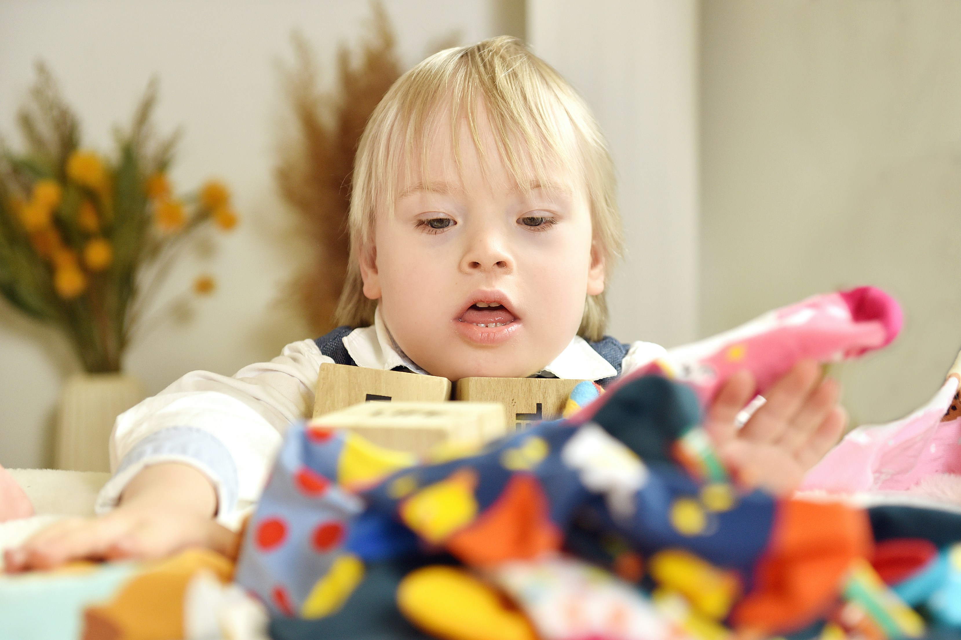 Young child helping to sort colourful socks into pairs on a living room floor