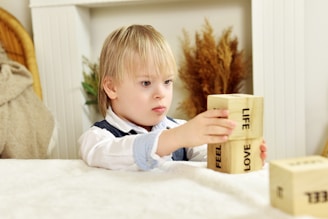 a little boy sitting at a table playing with blocks