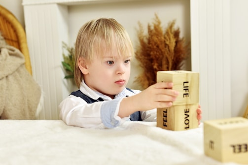 a little boy sitting at a table playing with blocks