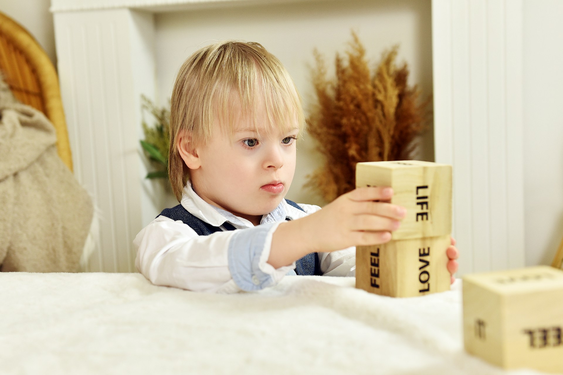 a little boy sitting at a table playing with blocks