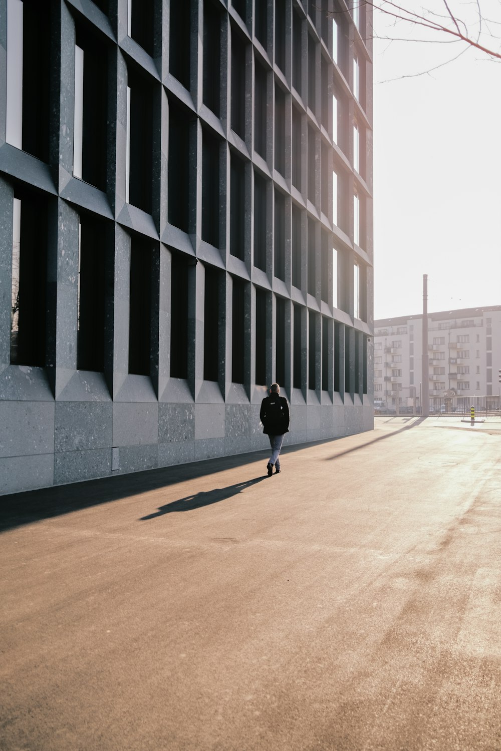 a person walking down a street next to a tall building