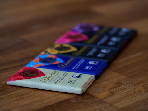 Close-up of a variety of colorful protein bars stacked on a rustic wooden table.
