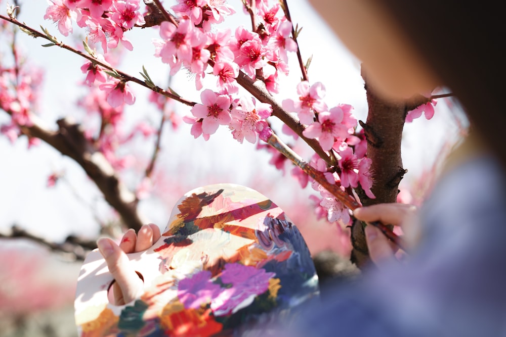 a woman in a kimono looking at a cherry blossom tree