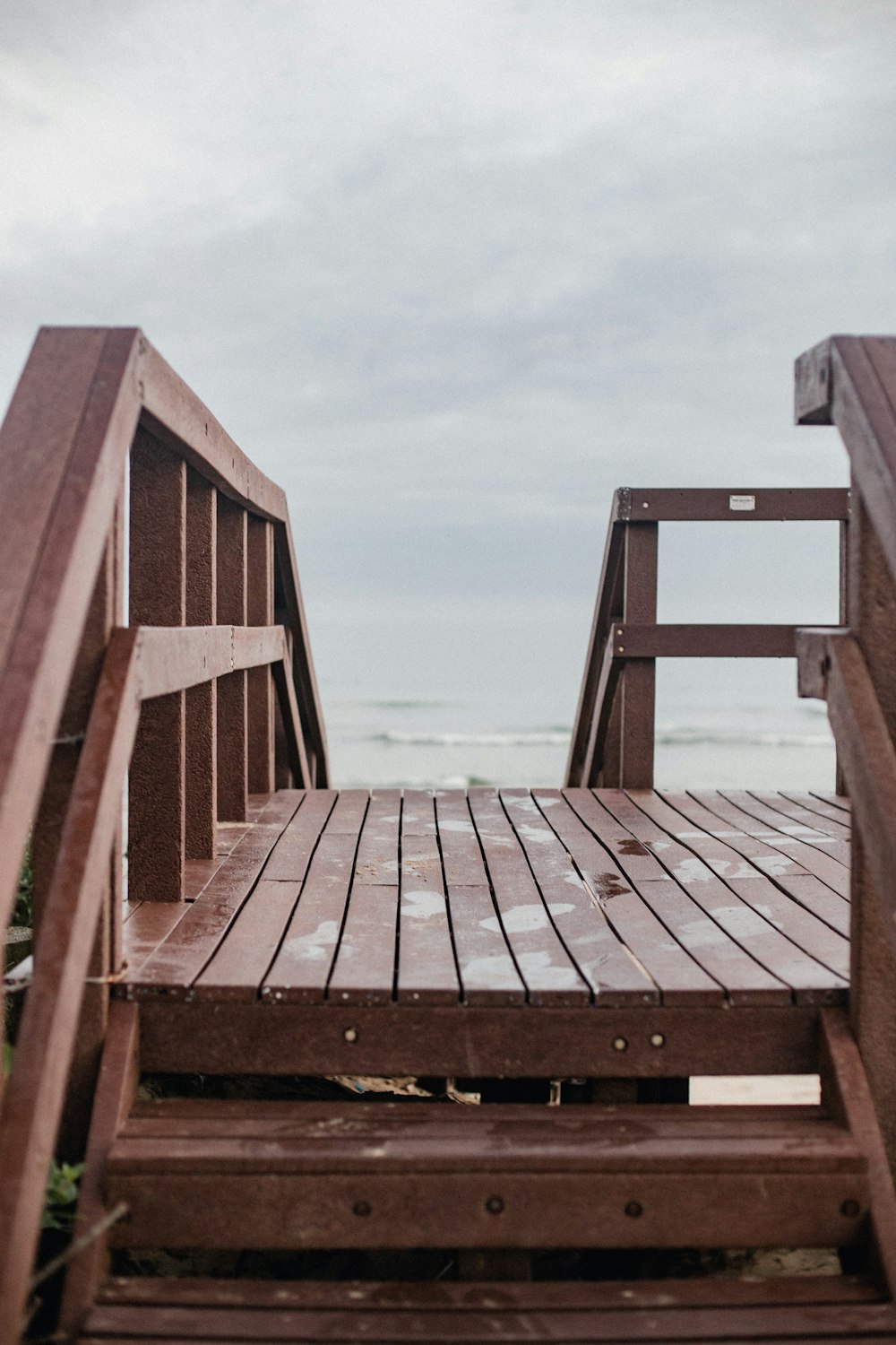 a wooden bench sitting on top of a beach next to the ocean