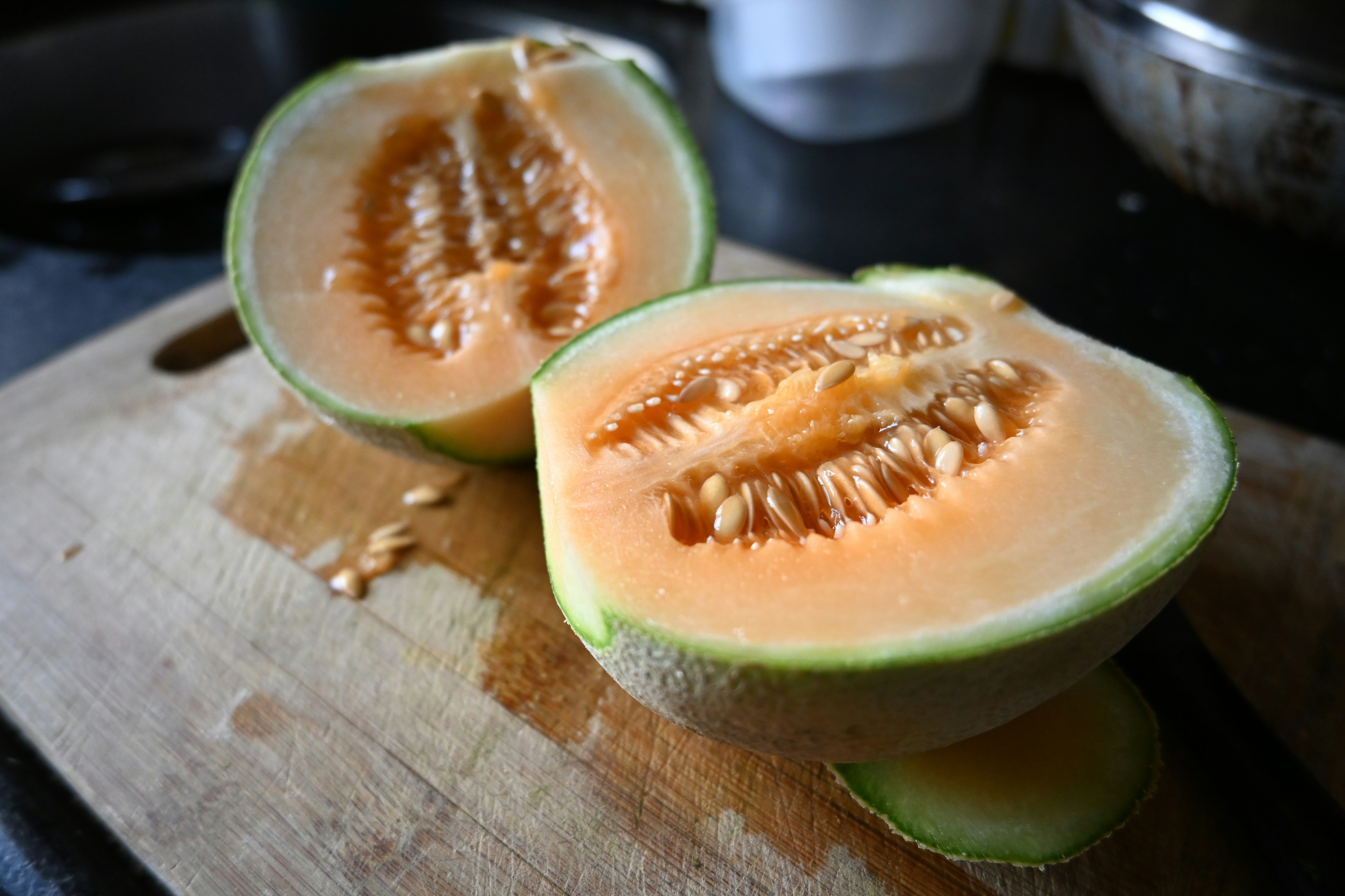 a cut up melon sitting on top of a wooden cutting board
