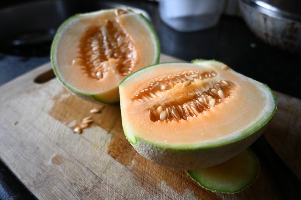a cut up melon sitting on top of a wooden cutting board