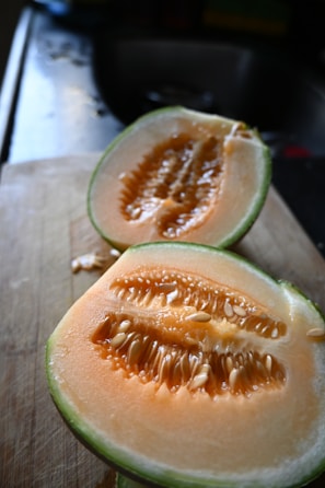 a couple of pieces of melon sitting on top of a wooden cutting board