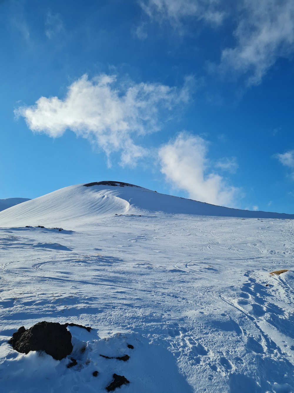 a snow covered hill with a blue sky in the background