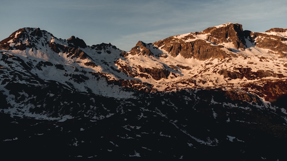 a large mountain covered in snow under a blue sky