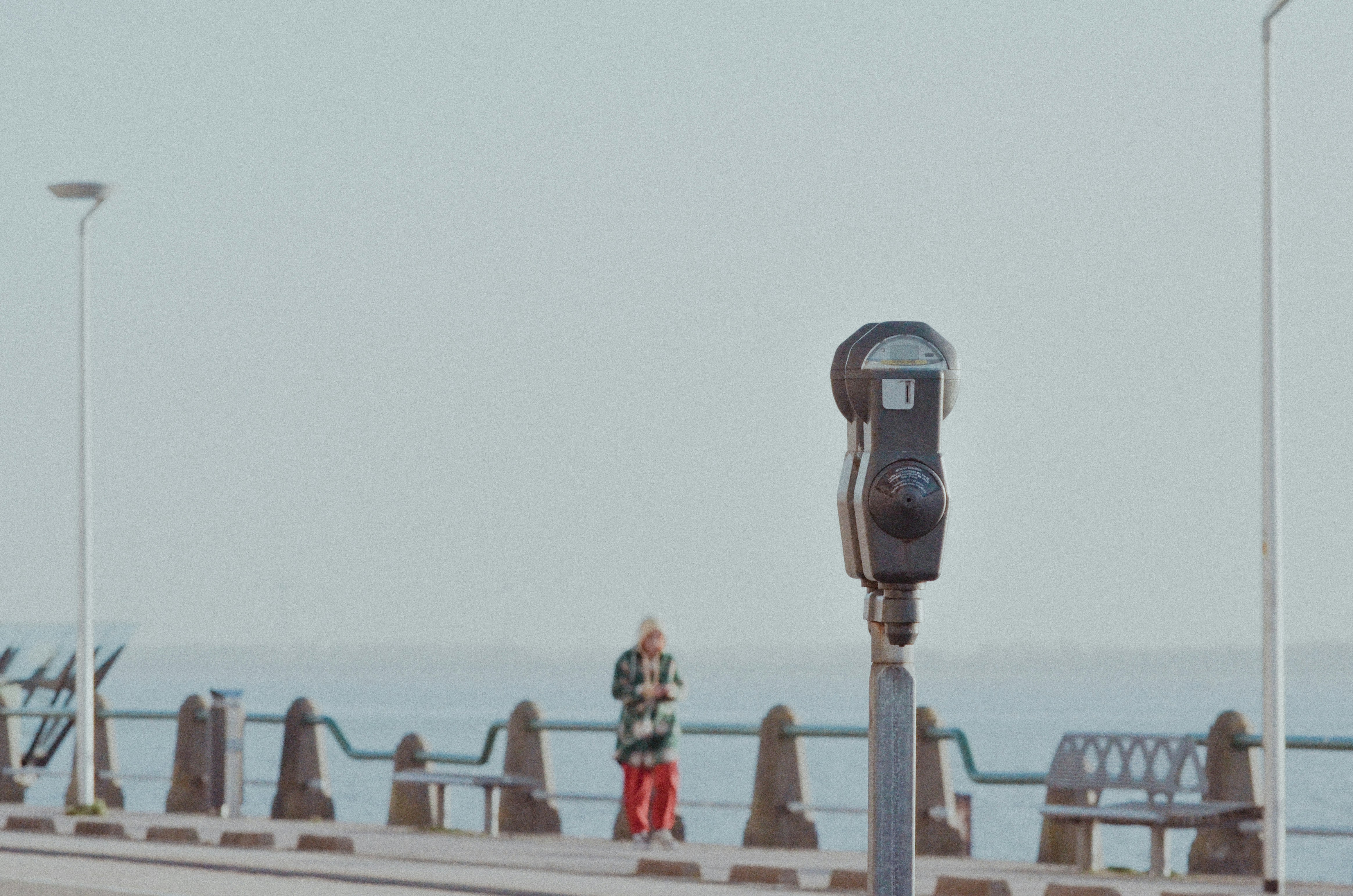 A parking meter sitting on the side of a pier photo – Free Grey Image ...
