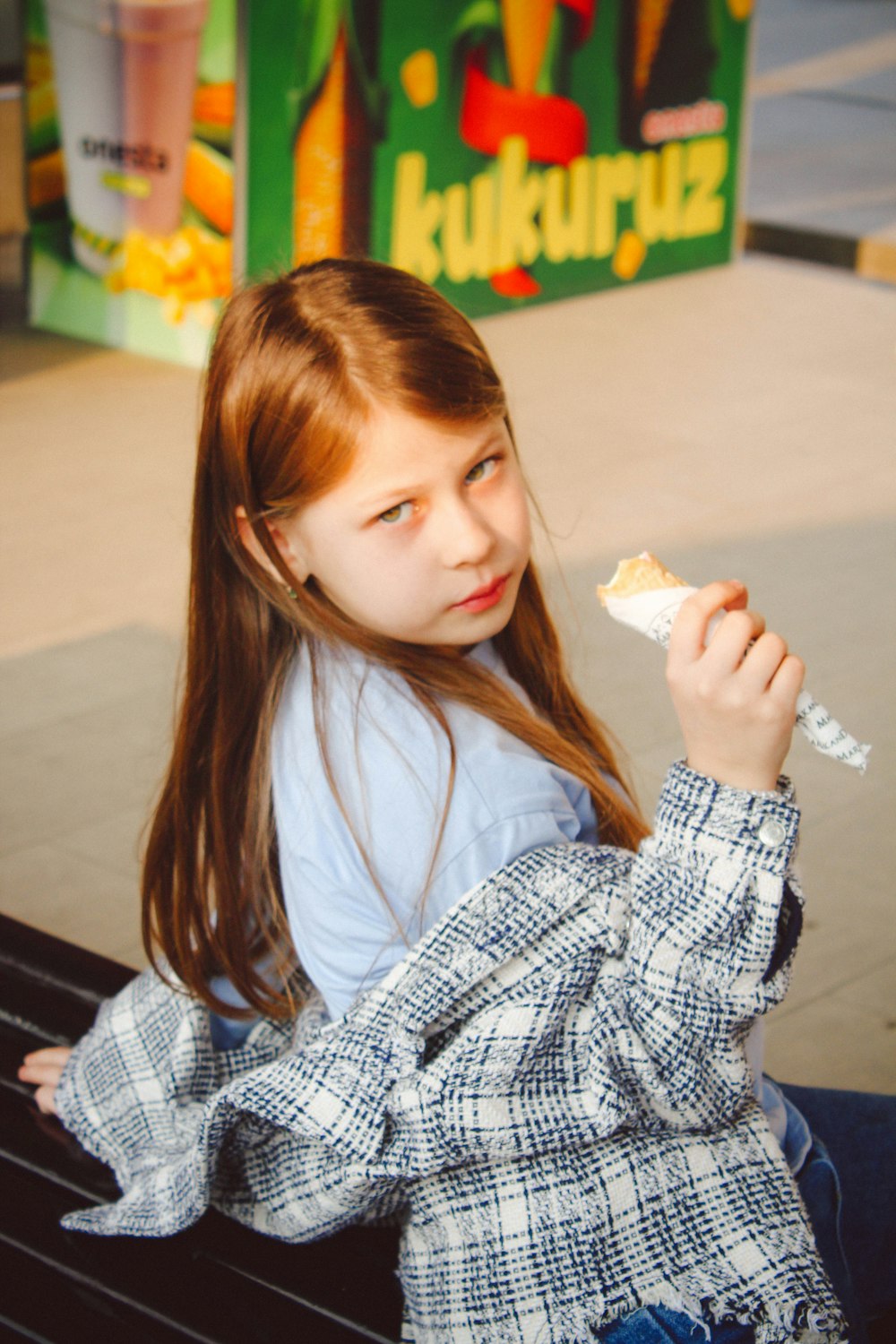 a little girl sitting on a bench eating food